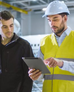 Team of Aircraft Maintenance Mechanics Moving through Hangar. Holding Tablet Computer